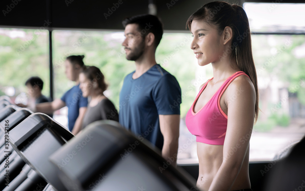 A group of healthy people walking on a treadmill at the fitness gym club. A group of healthy people walking on a treadmill at the fitness gym club.