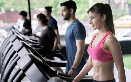 Fototapeta Naklejka Na Ścianę i Meble -  A group of healthy people walking on a treadmill at the fitness gym club.