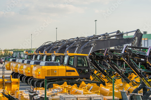 New Excavators are lined up in a parking lot.