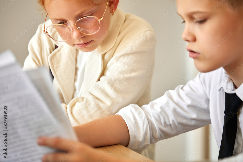 friendly kids couple behave themselves as adults, solve work problems together, look at laptop and documents, checking bills, making purchase online, freelance. children, people concept friendly kids couple behave themselves as adults, solve work problems together, look at laptop and documents, checking bills, making purchase online, freelance. children, people concept