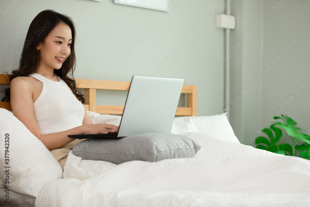 Beautiful Attractive Asian young woman lying on bed and using computer laptop for using social media and shopping online relax in cozy bedroom in holiday,Lifestyle in bedroom Concept Beautiful Attractive Asian young woman lying on bed and using computer laptop for using social media and shopping online relax in cozy bedroom in holiday,Lifestyle in bedroom Concept