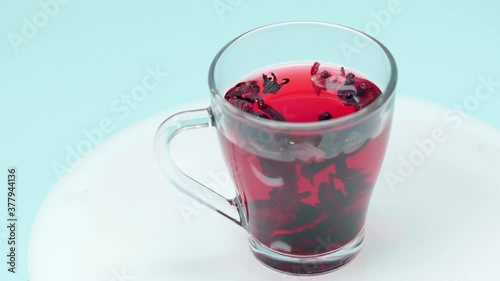 Cup of hibiscus tea spinning around isolated on blue photo