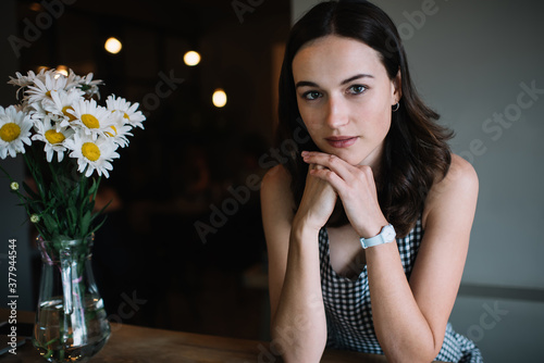 Pensive lady sitting at table with daisies