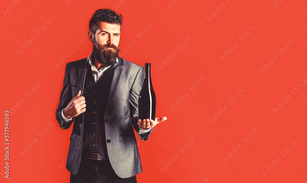 Bearded man with a bottle champagne of and glass. The person holds a red wine bottle in a hand. Stylish male in tuxedo, suit, jacket Bearded man with a bottle champagne of and glass. The person holds a red wine bottle in a hand. Stylish male in tuxedo, suit, jacket