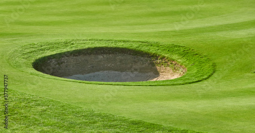 Circular bunker on the well-kept green lawn of a golf course