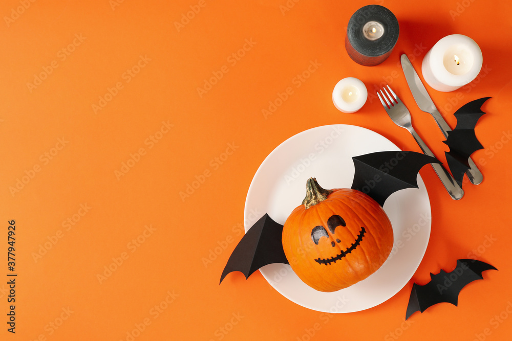 Table setting with halloween pumpkin on orange background