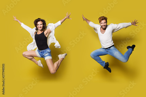 Jumping Couple, Full Length Young Happy People in Sport Dance, Isolated Yellow Background