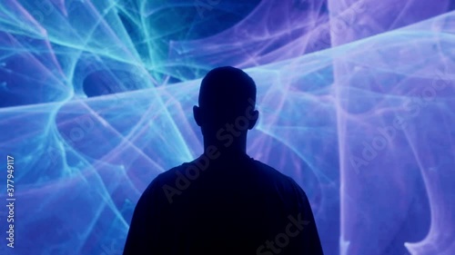 A silhouetted man stands in front of projected lights and animations photo