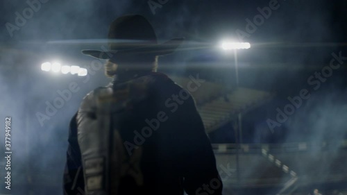 A cowboy walks through a well lit arena