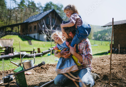 Obraz na płótnie Father with small children working outdoors in garden, sustainable lifestyle concept