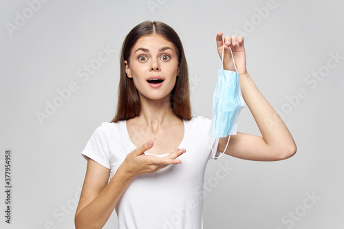 woman Wide open mouth surprised look medical mask in hand white t-shirt 