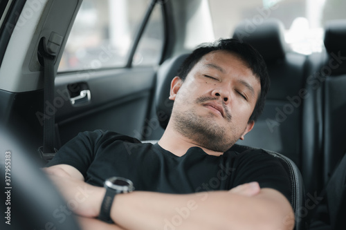 young asian man sleeping in his car. Sleepy not driving concept for the safety of driving a car on the road. © Looker_Studio