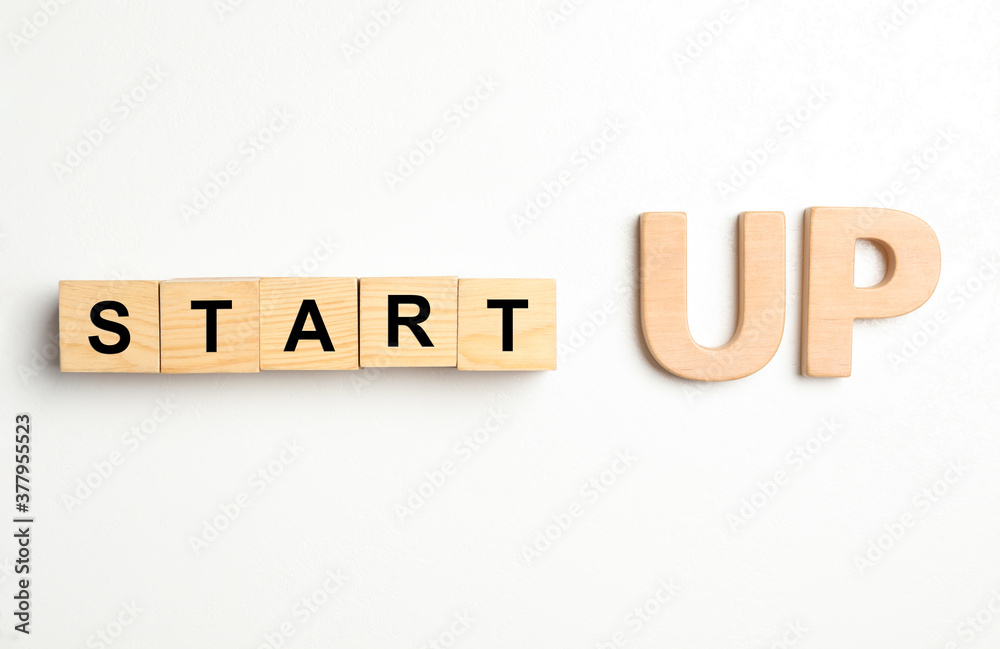 Words START UP made with wooden blocks on white background, flat lay Words START UP made with wooden blocks on white background, flat lay