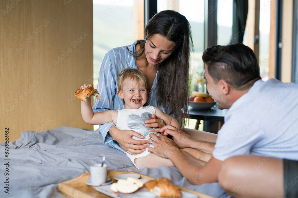 Young family with small daughter eating indoors, weekend away in container house in countryside. Young family with small daughter eating indoors, weekend away in container house in countryside.