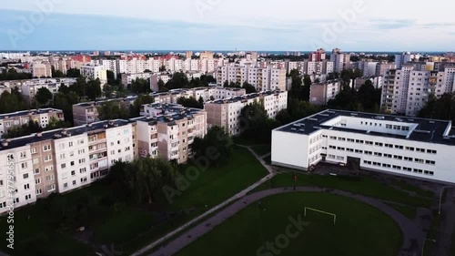 Evening aerial shot of Kalnieciai district in Kaunas while flying over school building and stadium with a lot of old soviet style block buildings photo