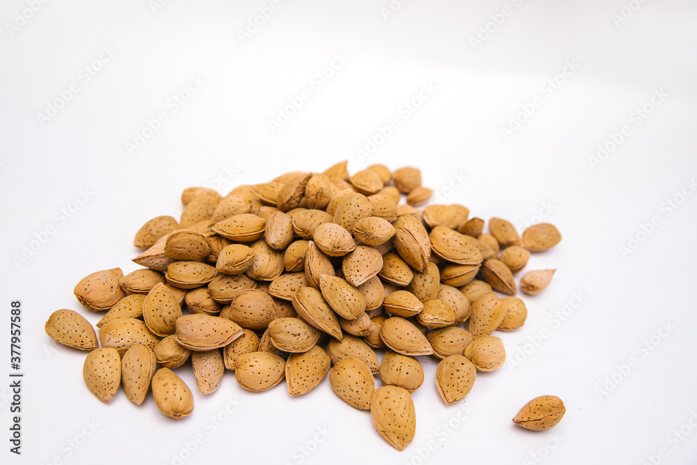 Inshell almonds on a white background. Almonds are arranged in a pile. Inshell almonds on a white background. Almonds are arranged in a pile.