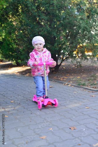 little beautiful girl riding scooter in park