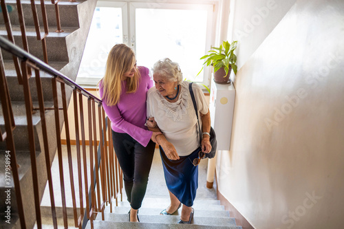 Caregiver helping senior woman climb staircase

