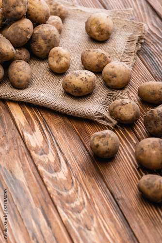dirty potatoes and burlap on wooden table