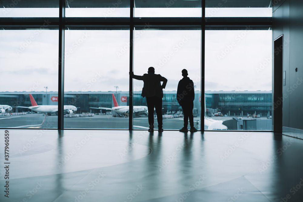 Anonymous people standing in front of window in airport hall
