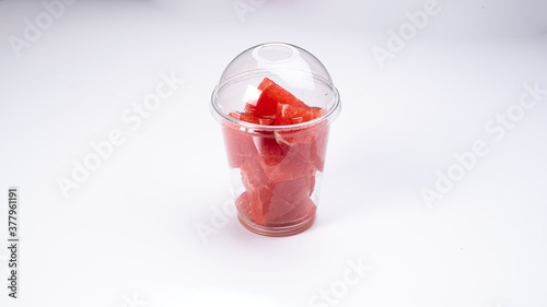 slices of red grapefruit in a plastic cup on a white background