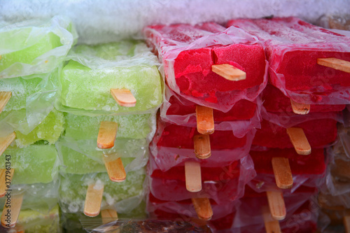 Many red and green Mexican frozen fruit paletas/popsicles in freezer