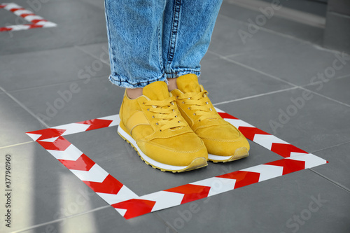 Woman standing on taped floor marking for social distance, closeup. Coronavirus pandemic photo