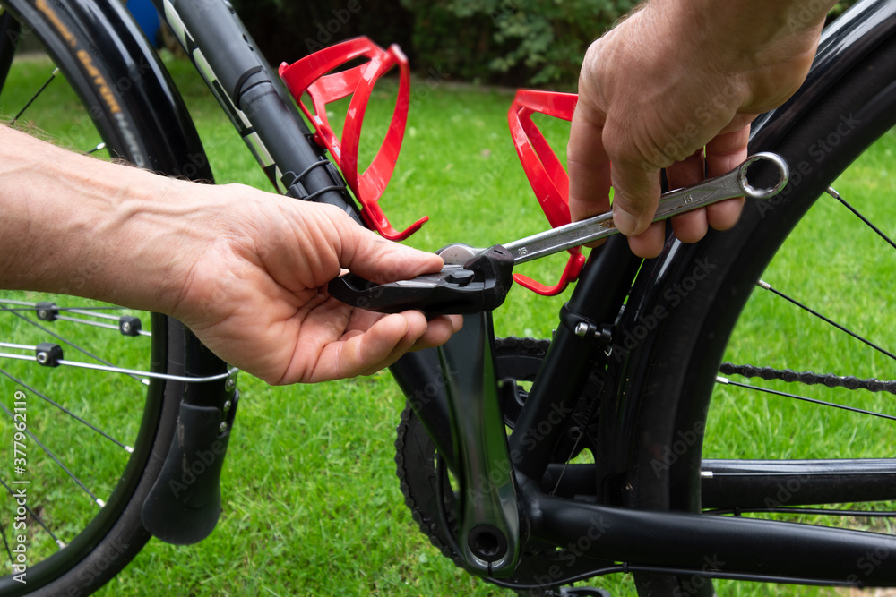 hand with spanner attaching bicycle pedals to the bike hand with spanner attaching bicycle pedals to the bike