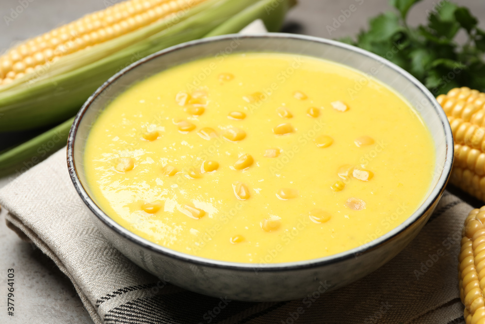 Delicious creamy corn soup on grey table, closeup Delicious creamy corn soup on grey table, closeup