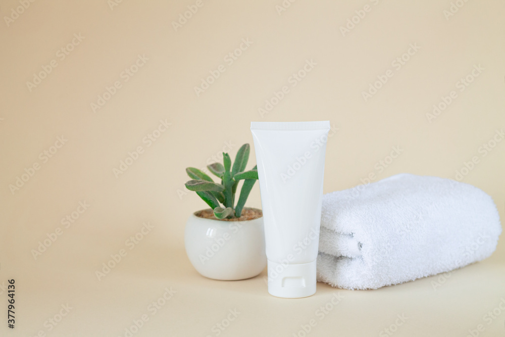 White blank cosmetic tube standing next to plant and towel White blank cosmetic tube standing next to plant and towel
