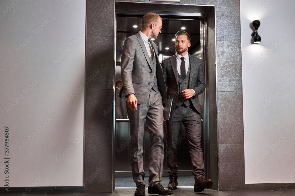 businessmen leave the elevator, two caucasian men after co-working. business people concept