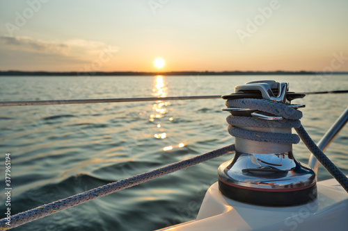 Sailing ship with winch in the lake or sea with light waves and sunset