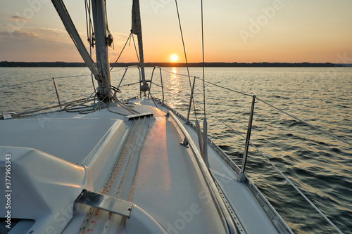 Fototapeta Naklejka Na Ścianę i Meble -  Sailing ship with winch in the lake or sea with light waves and sunset