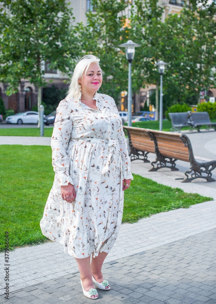 Plus size woman, American or European appearance walks in the city enjoying life. A young lady with excess weight, stylishly dressed in the center of the city. Natural beauty