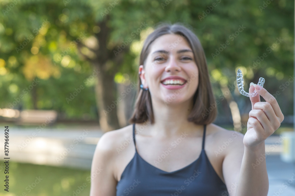 Beautiful smiling Turkish woman is holding an invisalign bracer Beautiful smiling Turkish woman is holding an invisalign bracer