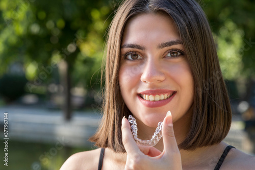 Beautiful smiling Turkish woman is holding an invisalign bracer photo