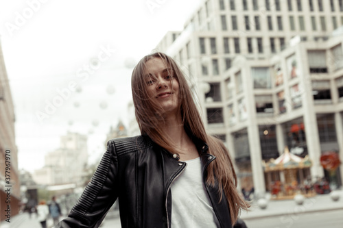 Smiling blonde girl with windy hair. Woman wearing black eco-leather jacket © darakaliton