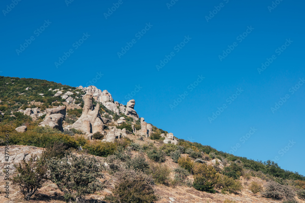 Ridge of brown rocks covered with greenery against a blue sky