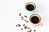 Pink and azure cups of fresh coffee with grains on white wooden background. Copy space