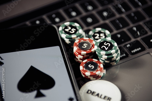 Poker play online concept. Poker chips, playing cards and smartphone on keyboard.
