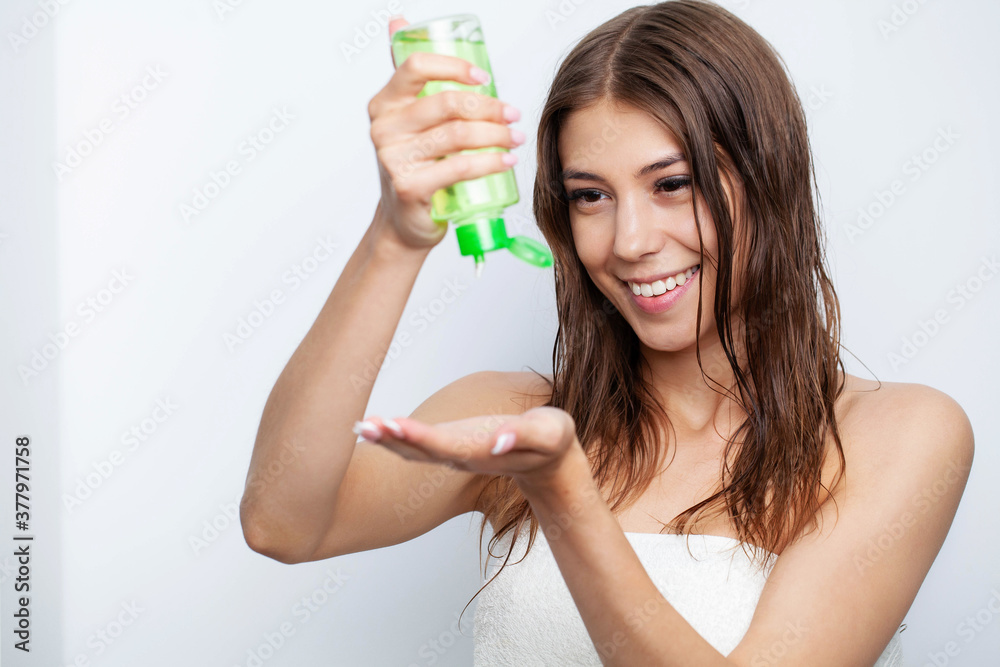 Young woman applying oil onto hair in bathroom Young woman applying oil onto hair in bathroom