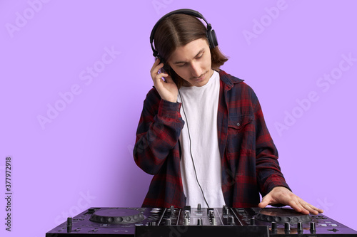 cool young DJ at work, spinning on turntable, mixing console. disco, club, music concept
