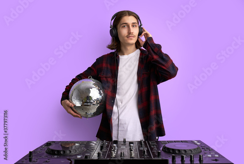 Fotografie young musician enjoy listening and performing music, club dj man stands with disco ball in hands