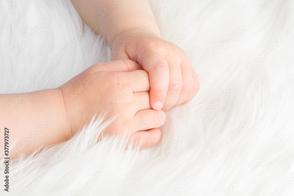 Baby girl hands on white, soft, fluffy fur blanket. Closeup. Cute moment. Baby girl hands on white, soft, fluffy fur blanket. Closeup. Cute moment.