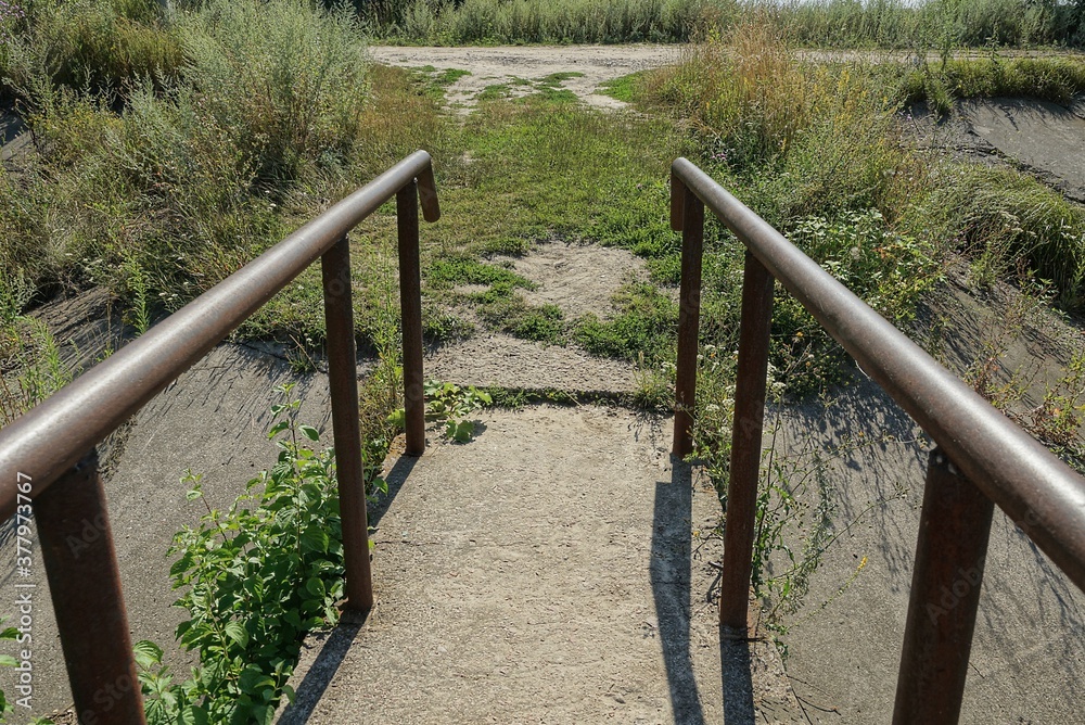 brown old iron rusty handrails made of pipes on a concrete bridge on the street against a background of green vegetation brown old iron rusty handrails made of pipes on a concrete bridge on the street against a background of green vegetation