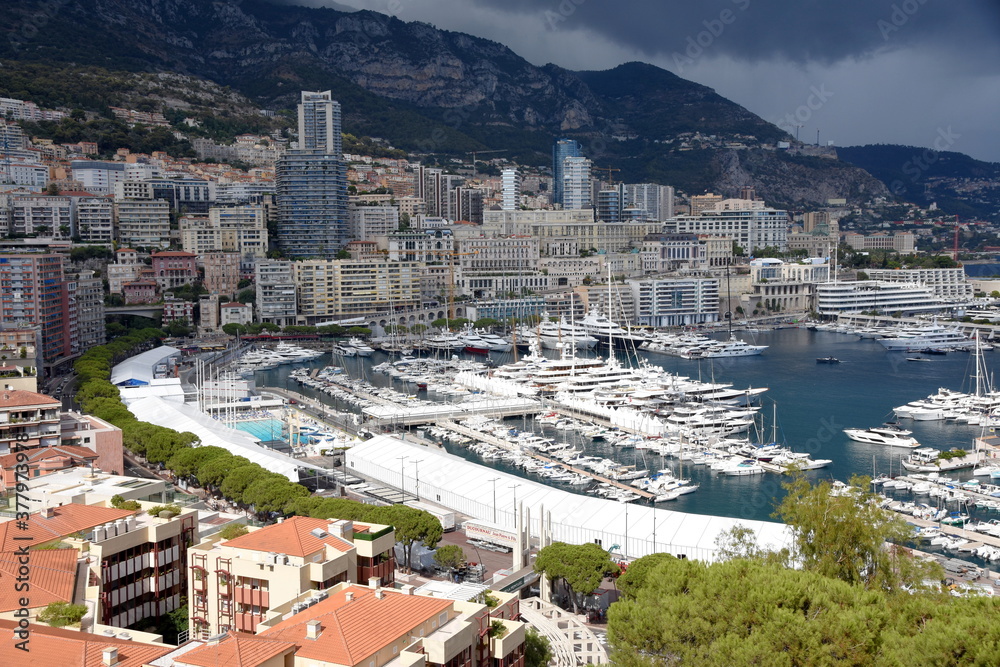 Monte Carlo with its marina and rocky hills on the background. The threatening dark clouds pull over the city. 