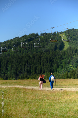 Couple of tourists go on a mountain road on a hike