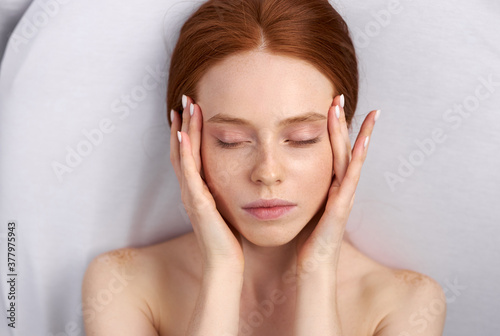 top view portrait of redhead woman touching face after beauty procedures, relax
