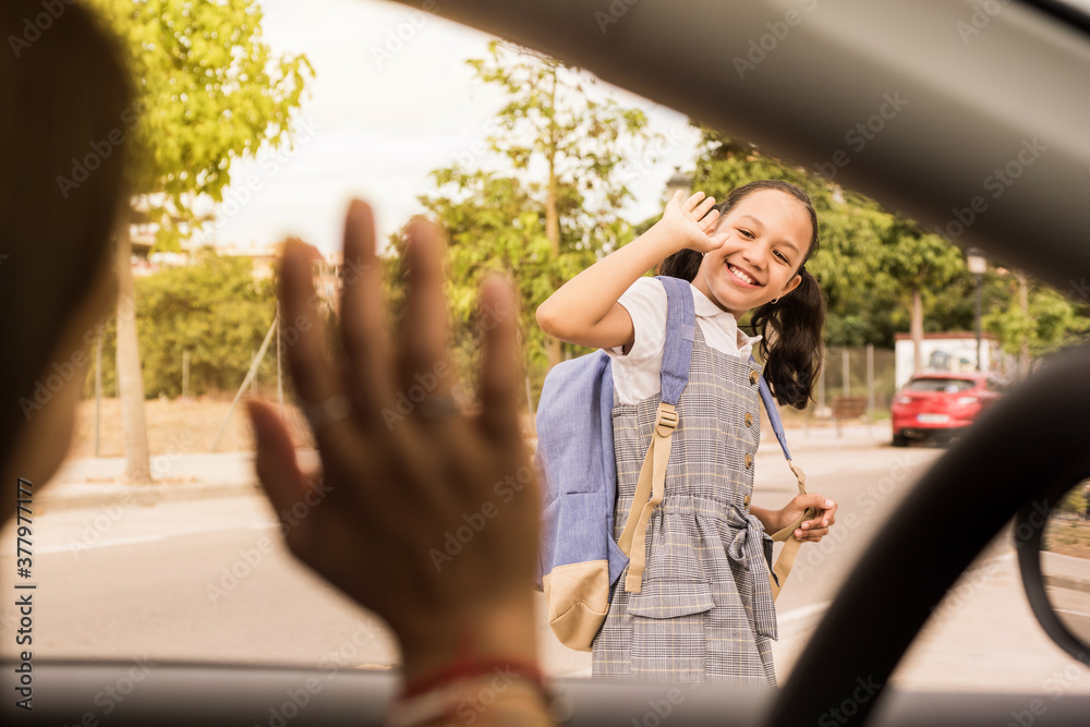 View from the car schoolgirl saying goodbye with the hand. Smiling