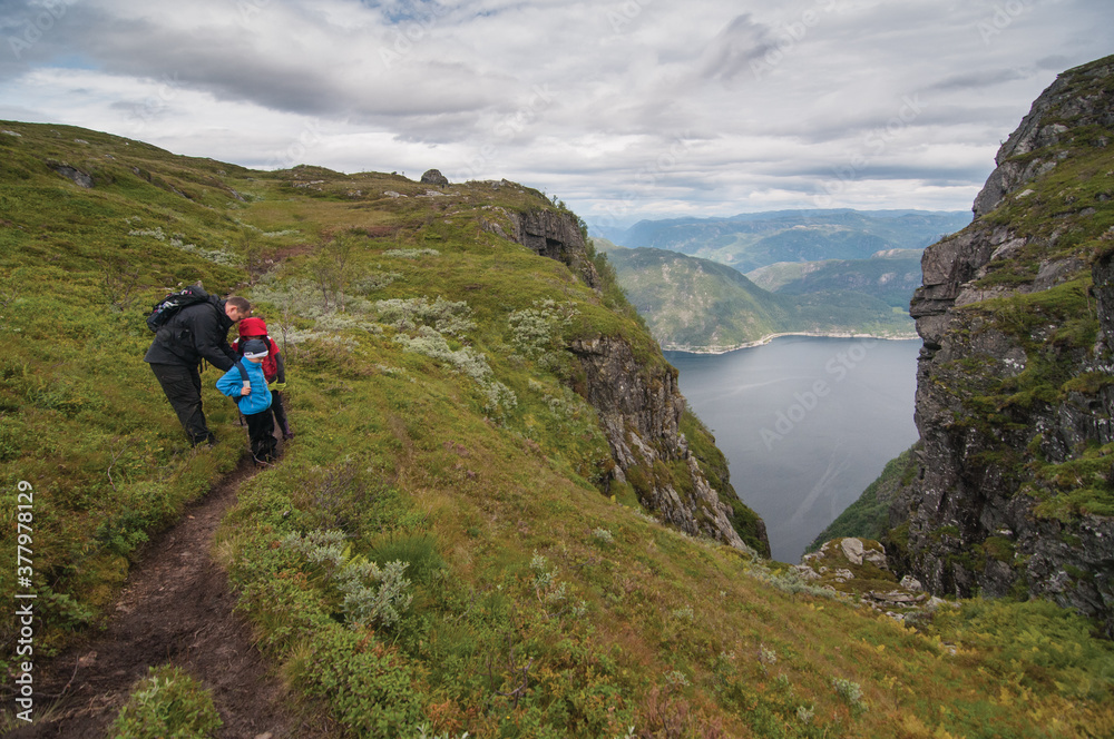 Horizontal photo of the family of three is on their way to hike in the norwegian montains in the fjord